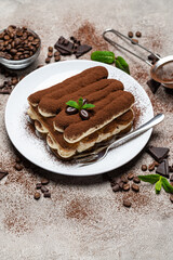 Classic tiramisu dessert on ceramic plate on concrete background