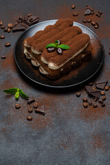 Classic tiramisu dessert on ceramic plate on concrete background