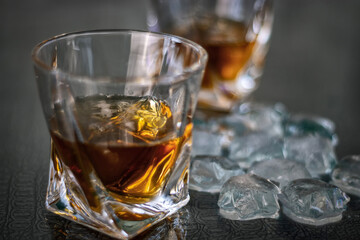 Glasses of whiskey and ice are on the table. Close up