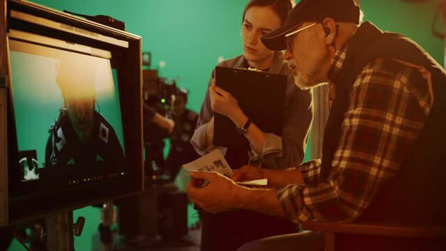 Director Looks at Display and Compares to Storyboard while Shooting Blockbuster Movie. Green Screen Scene with Actor Wearing Motion Caption Suit. Film Studio Professional Crew Doing High Budget Movie