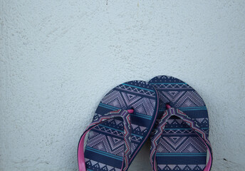 Colorful flip flops on white wall.