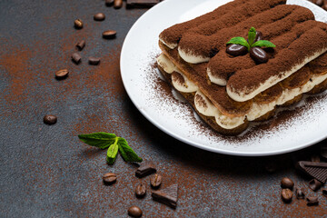 Classic tiramisu dessert on ceramic plate on concrete background