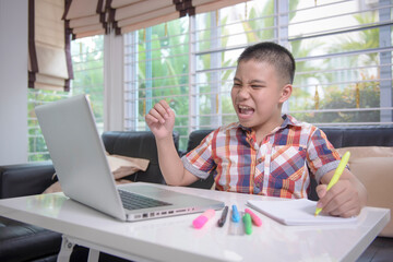 An Asian male student is very happy. That can answer teacher homework questions correctly in studying online via the internet at home. Due to the coronavirus crisis (Covid-19). Home learning concepts.