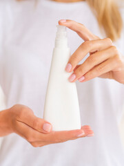 Plastic pump triangular bottle for a gel or mousse. Feminine hands hold White clean jar with space for your logo. Vertical front view cosmetic mockup