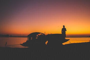 Naklejka na ściany i meble silhouette of a fisherman on the sunset