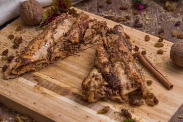 Traditional Walnut and Carob Crepes on a Wooden Cutting Board Decorated With Cinnamon, Raisins and Whole Walnuts