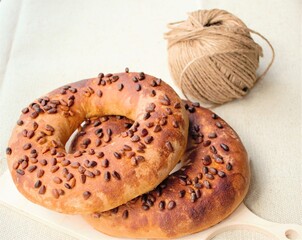 Composition on bright linen: two ruddy homemade bagels with pine nuts and a tangle of rough packing rope on the far lan (the focus on it is specially blurred, bokeh)