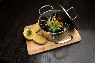 mussels in pan with lemon on wooden board