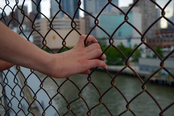Hands on metal fence with blurred background in nasty weather.