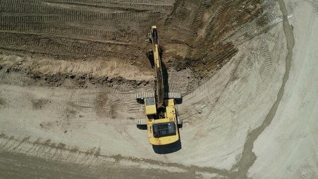 Top-Down View . An Industrial Excavator On An Open Road Section Digs The Ground An Unmanned Image Of A Construction Site.