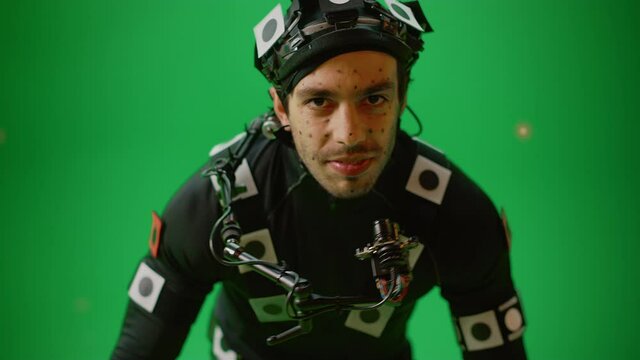 Actor Wearing Motion Caption Suit and Head Rig acts as an Animal or a Monster for CGI Green Screen Scene. Big Budget Filmmaking On Film Studio Set Shooting Blockbuster Movie with Chroma Key. Closeup