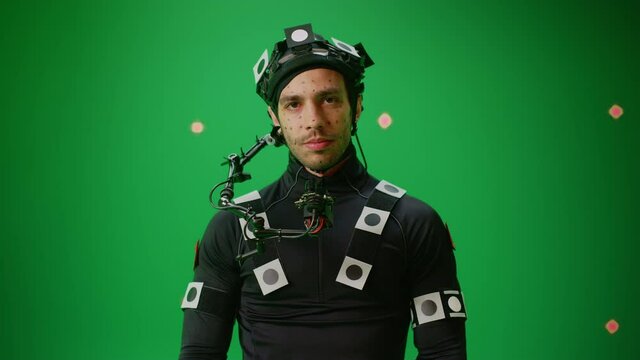 Portrait of an Actor Wearing Motion Caption Suit and Head Rig Posing with Green Screen Background. Big Budget Filmmaking On Film Studio Set Shooting Blockbuster Movie with Chroma Key. Medium Shot