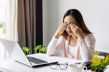 Tired and stressed young asian woman feel pain eyestrain and rubbing her eyes and take off her...