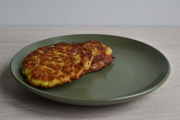 Traditional Belarusian fried potato pancakes on a green plate.