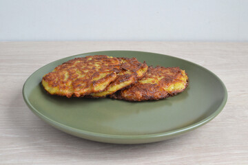 Traditional Belarusian fried potato pancakes on a green plate.