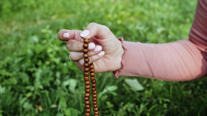 Woman lit hand close up counts rosary - malas strands of gemstones beads used for keeping count...