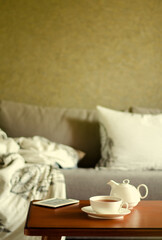 Fototapeta na wymiar Cozy home interior with teapot, cup of tea and eBook