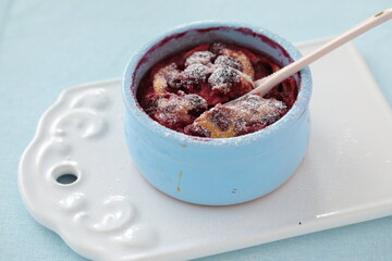 Cherry clafoutis topped with powdered sugar in a blue pot