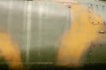Khaki background. The old metal surface of the fuselage of a military aircraft with rivets.