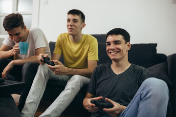 teenager boys having fun playing games on console at home