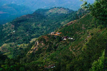 View from above to the green mountains, pathway, smoke and village in Sri Lanka