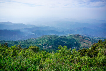 Naklejka premium View from above to the green mountains, pathway, smoke and village in Sri Lanka..