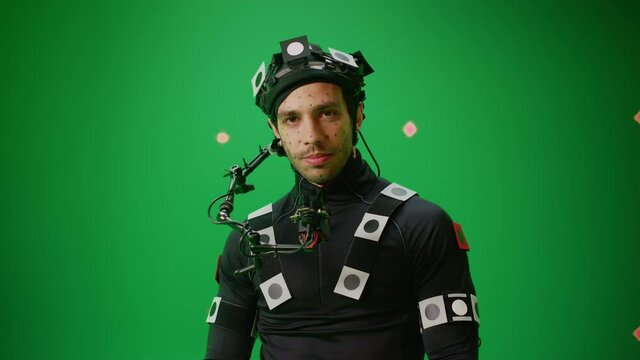 Portrait of an Actor Wearing Motion Caption Suit and Head Rig Posing with Green Screen Background. Film Studio Set Shooting Blockbuster Movie with Chroma Key. Medium Shot Looking at Camera