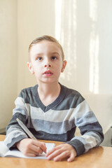 Naklejka premium little boy writes his first school assignments