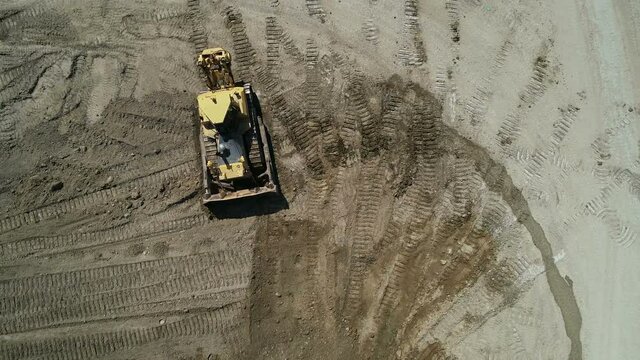 Top-Down View . Industrial Bulldozer On An Open Road Section .Unmanned Image Of A Construction Site.A Bulldozer Rakes The Ground.