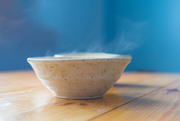 Two ceramic bowls with a hot dish on a wooden table on a blurred background.