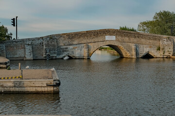  The old and traditional stone bridge over the River Thurne in the village of Potter Heigham in the Norfolk Broads National Park capture on a sunny evening