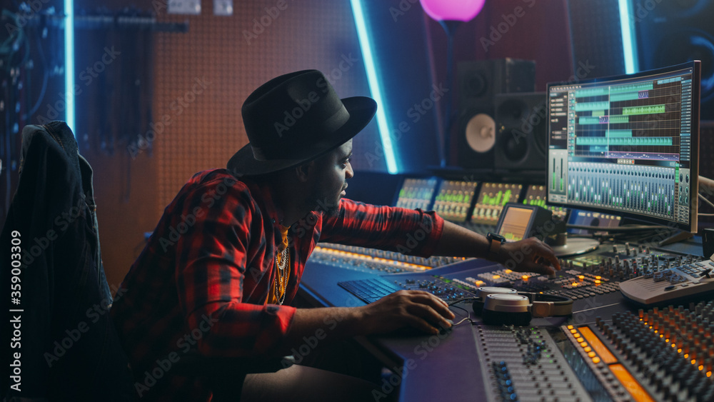 Wall mural Portrait of Audio Engineer Working in Music Recording Studio, Uses Mixing Board Create Modern Sound. Successful Black Artist Musician Working at Control Desk. Having Fun, Smiling.