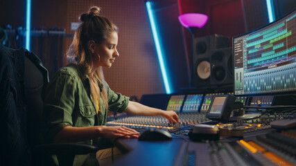 Beautiful, Stylish Female Audio Engineer and Producer Working in Music Recording Studio, Uses Mixing Board and Software to Create Cool Song. Creative Girl Artist Musician Working to Produce New Song - obrazy, fototapety, plakaty