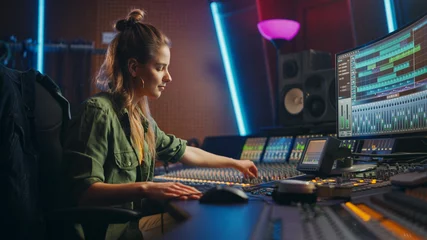 Poster Beautiful, Stylish Female Audio Engineer and Producer Working in Music Recording Studio, Uses Mixing Board and Software to Create Cool Song. Creative Girl Artist Musician Working to Produce New Song © Gorodenkoff