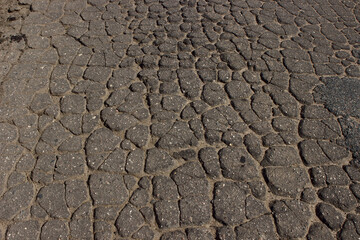 Cracked dry surface of an old gray asphalt road.