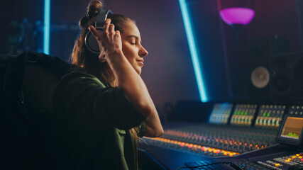 Portrait of Beautiful Female Artist Musician in Music Recording Studio Putting on Headphones. She...