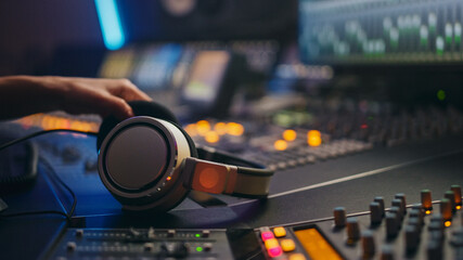 Close-up Shot of a Headphones lying on Mixing Board in Music Recording Studio. Successful Female Audio Engineer Creates Modern Song.