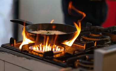 Pan of food sizzling on a gas hob