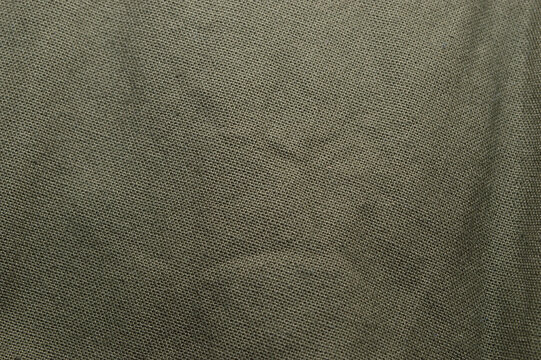 Green fabric texture as background. Coloring of khaki military clothing.