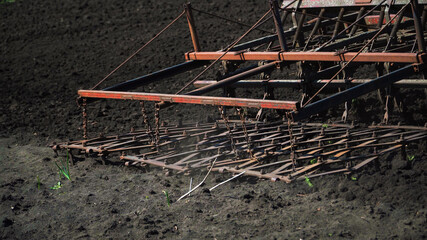 The tractor cultivates and cuts furrows in the field. Tractor work in the black soil field in the village