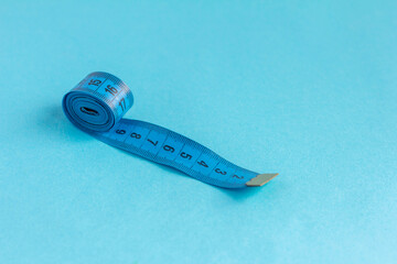 A roll of blue measuring tape on a blue background.