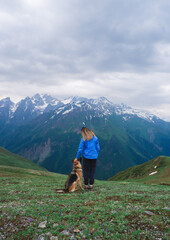 A girl traveler and a dog stay in the mountains, Georgia, Svaneti