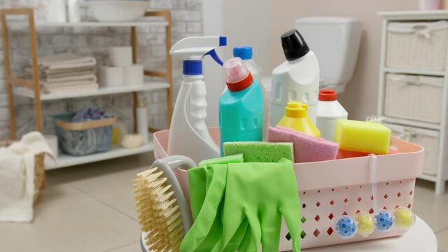 Housewife taking bottle of detergent from basket in bathroom