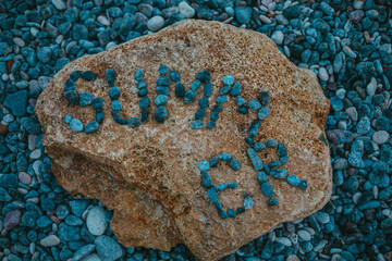 The inscription summer gray pebbles on an orange stone