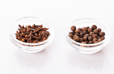 cloves and allspice in transparent bowls, isolated on a white background