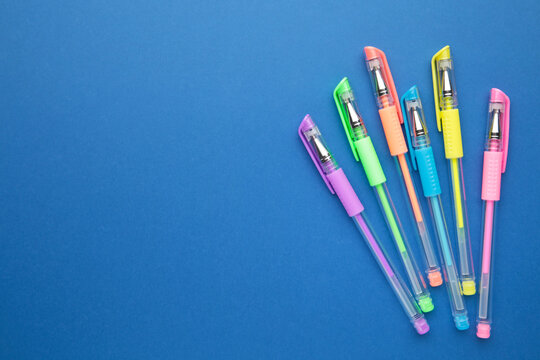 Set of colored pens on blue paper background with copy space