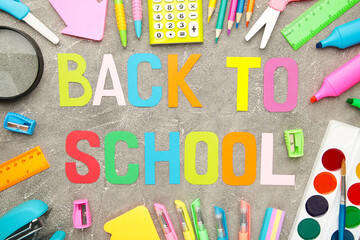 School supplies with inscription back to school on grey concrete background