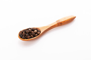 black pepper peas in a wooden spoon and scattered isolated on a white background