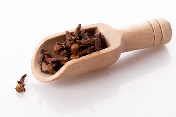 clove seasoning in a wooden spoon isolated on a white background