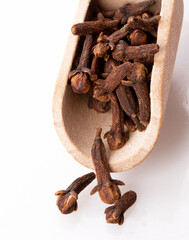 clove seasoning in a wooden spoon isolated on a white background